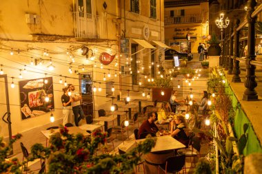 Tropea - Kalabrien - İtalya - 05-30-2025: İnsanlar Tropea, Calabria, İtalya 'da bir açık hava restoranında akşam yemeği yiyorlar..