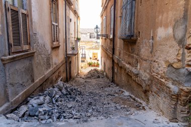 Pizzo - Kalabrien - İtalya - 06-02-2025: Pizzo, Calabria 'daki eski binalar arasında dar bir ara sokak, yol çalışması kalıntıları ön planda açıkça görülüyor.