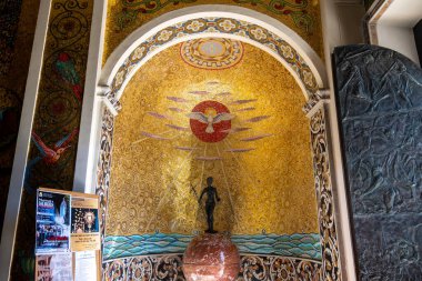 Reggio Calabria - Kalabrien - İtalya - 05-25-2025: İtalya 'nın güneyindeki Reggio Calabria' daki süslü bir kilise köşesinde parlak bir güvercin ve kırmızı bir diskin yer aldığı altın bir mozaik.