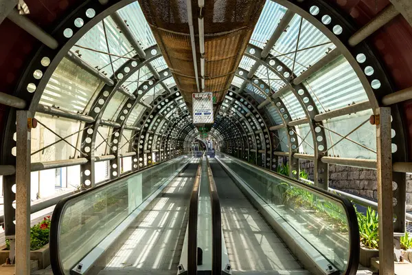 Reggio Calabria - Kalabrien - 05-22-2025: Reggio Calabria 'da cam paneller, metal kirişler ve doğal gün ışığında fabrikalarla çerçevelenen kapalı yürüyen merdiven tünelinin iç görünümü.