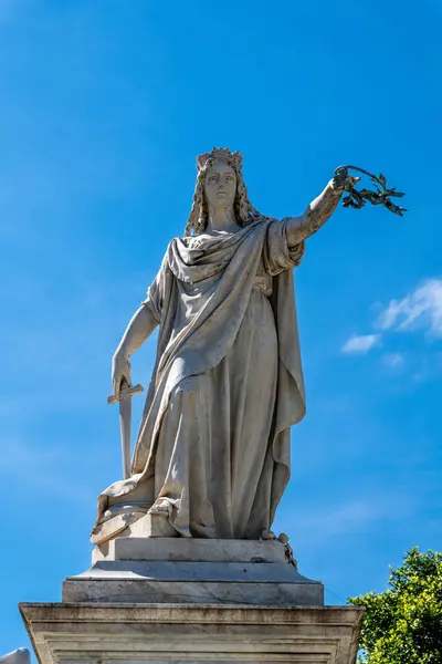 Reggio Calabria - Kalabrien - 05-22-2025: Açık mavi gökyüzü altında, Monumento ai Martiri 'nin bir parçası olan kılıç ve defne dalı tutan taçlı kadın heykeli.