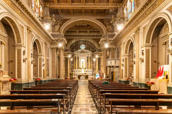 Reggio Calabria - Kalabrien - 05-22-2025: Reggio Calabria 'da Chiesa del Santo Rosario' nun merkezi koridoru ahşap banklar, süslü sütunlar, avizeler ve ılık ışık sunakları