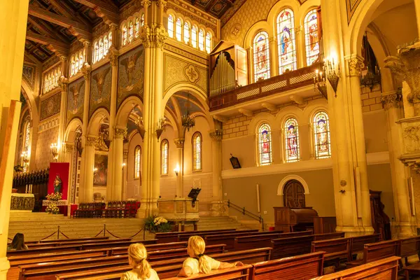 Reggio Calabria - Kalabrien - 05-22-2025: Vitraylı pencereleri, kemerleri, bankları, organ boruları ve sunağın yanında oturan iki ziyaretçisi olan Reggio Calabria Katedrali.