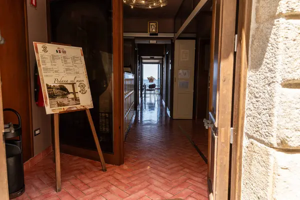 Scilla - Kalabrien - 05-27-2025: Scilla, Calabria 'da bir restoran koridoruna bakın, menü işaretini, fayanslı zemini, koridoru ve arka planda deniz olan masayı gösteriyor