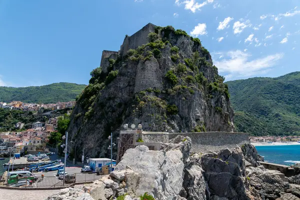 Scilla - Kalabrien - 05-27-2025: Arka planda küçük liman, deniz ve yeşil tepeler bulunan Scilla kıyı şeridi üzerindeki dik kayalık bir kayalık kayalık üzerinde Castello Ruffo manzarası.