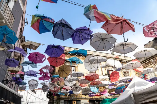 Catania, Sizilien - İtalya - 04-15-2025: Katanya, Sicilya 'daki binalar arasındaki kablolara asılmış sayısız renkli şemsiye dar bir sokak üzerinde yüzen bir kubbe oluşturuyor.