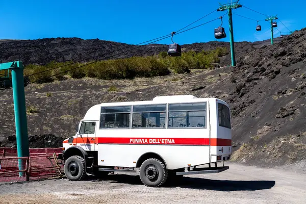Catania, Sizilien - İtalya - 04-22-2025: Berrak mavi gökyüzünün altındaki volkanik yamaçlarda, Etna 'ya Seyahatler için beyaz bir off-road turist otobüsü.