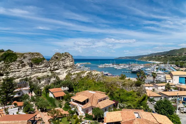 Tropea - Kalabrien - İtalya - 05-30-2025: Tropea, Kalabrien 'deki liman ve kasaba binaları, kayalık kayalıklar ve Akdeniz kıyısı boyunca demirlemiş yatlar.