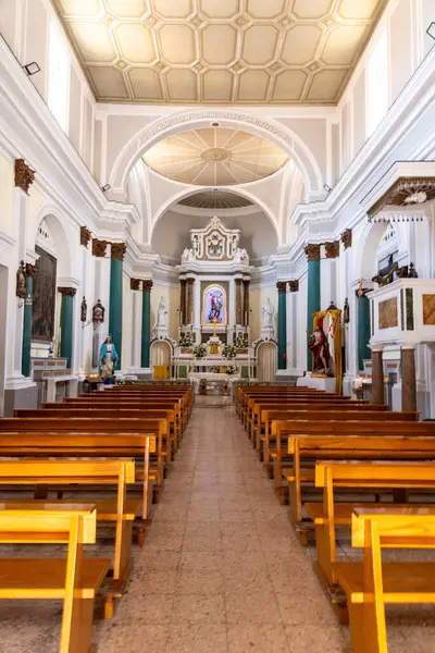 Tropea - Kalabrien - İtalya - 05-30-2025: Tropea, Calabria 'daki San Michele Kilisesi' nin içi, ahşap sıralar, dini heykeller ve parlak ışık altında zengin bir sunağı gösteriyor..