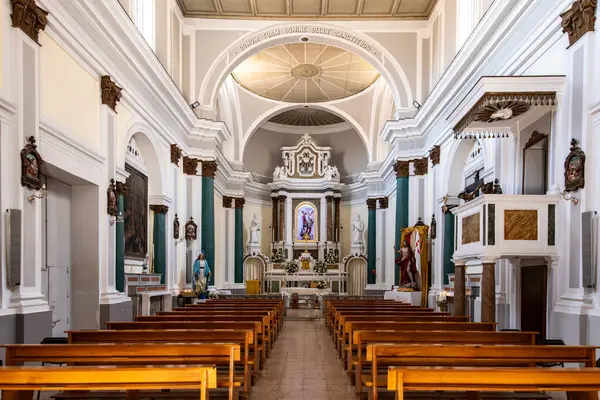 Tropea - Kalabrien - İtalya - 05-30-2025: Tropea, Calabria 'daki San Michele Kilisesi' nin içi, simetrik ahşap sıralar, heykeller ve dini sanat eserleriyle süslü bir sunak göstermektedir..