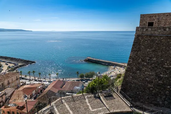 Pizzo - Kalabrien - İtalya - 06-02-2025: Açık bir yaz gününde Calabria 'daki Pizzo' nun kıyı şeridi, sahil şemsiyeleri, eski kasaba çatıları ve kale duvarı ile manzarası yükseltildi.