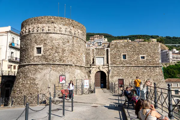 Pizzo - Kalabrien - İtalya - 06-02-2025: Silindirik kulesi ve dikdörtgen bloğu olan taş kale, önde gözleyen ve dinlenen turistler, güneşli hava ve mavi gökyüzü.