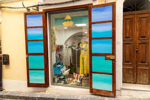 Pizzo - Kalabrien - İtalya - 06-02-2025: Pizzo, İtalya 'da küçük bir moda butiğinin sokak manzarası, vitrininde mavi panjurlar ve yaz kıyafetleri sergileniyor.