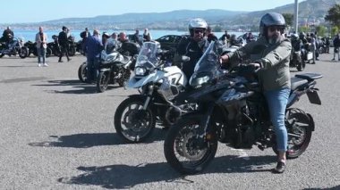 Motosikletçiler Reggio Calabria 'da bir sahil meydanında toplanır, motorları çalıştırır, birbirlerini selamlar ve grup yolculuğuna hazırlanırlar..