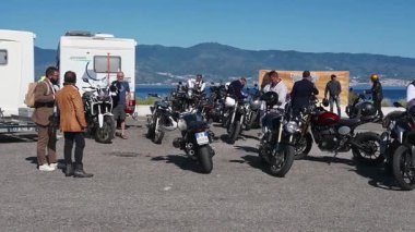 Katılımcılar ve klasik motosikletler, seçkin beyefendiler için Reggio Calabria kıyısı boyunca toplanıyor..