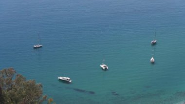 Sicilya, Taormina yakınlarında demirleyen birkaç tekne, aşağıdaki kıyı bölgesinde görünen turkuaz su ve ağaçlarla birlikte görüldü..