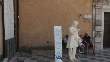 Oscar Wilde 'ın gerçek boyutlardaki heykeli Taormina, Sicilya' da hareketsiz duruyor. İnsanlar yanından geçerken ve kamera sabit duruyor..