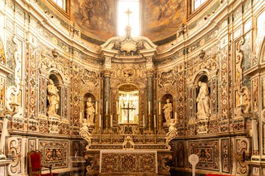 Taranto - Puglia - Italien - 06-17-2025: Mermer kabartmalar, heykeltraşlar, altın şamdanlar ve zengin dekore edilmiş bir şapelin içindeki süslü duvar panelleri ile Barok sunağı.