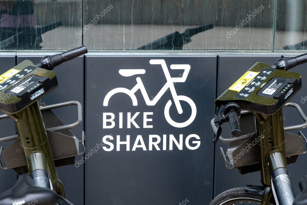 Matera - Basilikata - Italien - 06-16-2025: Close-up of two rental bicycles in a docking station with bike sharing sign and visible brand markings on handlebars and electronic panels.