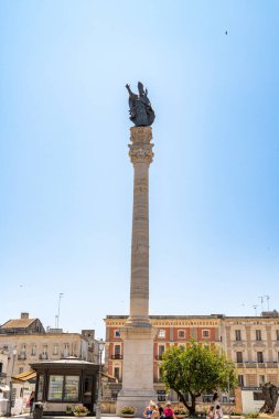 Lecce - Lecce - İtalya - 06-21-2025: Lecce 'deki Colonna di SantOronzo' da üzerinde bir heykel bulunan uzun bir sütun yer alıyor..