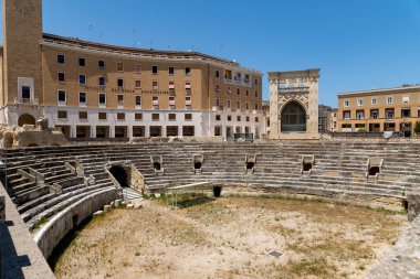 Lecce - İtalya - 06-21-2025: Lecce Roma Amfitiyatrosu kısmen korunmuş ve İtalya 'nın Lecce kentinin merkez meydanında modern mimari ile çevrelenmiştir..