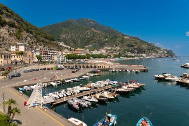 Amalfikueste - Kampanien - Italien - 07-04-2025: Arka planda çok sayıda demirlemiş tekne, çevresindeki binalar ve Amalfi - İtalya tepeleri bulunan bir marina ve sahil gezisi manzarası.