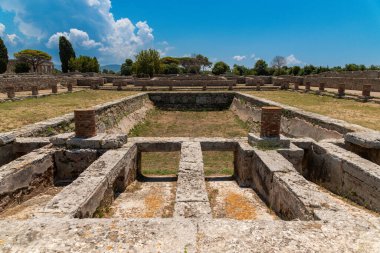 Capaccio Paestum - Kampanien - Italien - 07-06-2025: Paestum 'da taş duvarları ve mavi gökyüzünün altında silindirik tuğla sütunları olan batık yapıları gösteren antik bir arkeolojik alan.