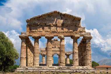 Capaccio Paestum - Kampanien - Italien - 07-06-2025: Paestum arkeolojik sahasında bulunan mavi gökyüzü altındaki taş sütunlarla korunmuş Doric tapınağının önden görünüşü.