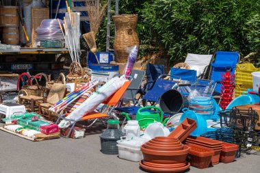 Capaccio Paestum - Kampanien - Italien - 07-10-2025: Sandalyeler, sepetler ve saksılar da dahil olmak üzere çeşitli ev ve bahçe eşyaları bir kamyonun önünde güneşli bir sokak pazarında sergileniyor.