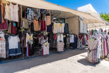 Capaccio Paestum - Kampanien- Italien- 07-10-2025: Elbise ve fiyat tabelalı birden fazla giyim rafı bir seyyar dükkanının önündeki bir sokak pazarının altında sergileniyor.