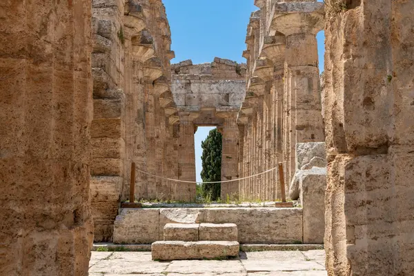 Capaccio Paestum - Kampanien - Italien - 07-06-2025: Güney İtalya 'daki Paestum antik tapınak kalıntıları, simetrik taş sütunlar ve mavi gökyüzünün altındaki merkezi merdivenleri gösteriyor.