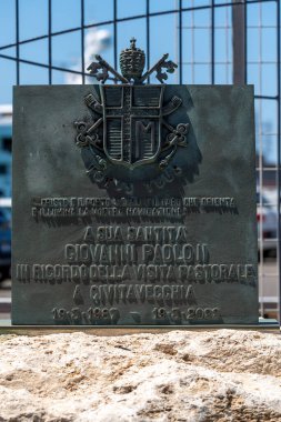 Civitavecchia - Latium - Italien - 07-31-2025: Papa 2. John Paul 'un armasını ve Civitavecchia ziyaretini onurlandıran İtalyanca bir yazıyı gösteren bir bronz plaka.