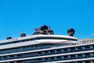 Civitavecchia - Latium - Italien - 07-31-2025: Modern bir yolcu gemisinin üst kısmı açık mavi gökyüzü altında birden fazla siyah kubbe, egzoz bacası ve cam balkon gösteriyor.