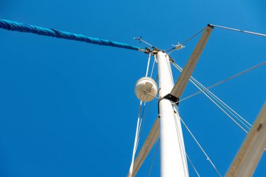 Nydri - İyon Adaları - Yunanistan - 08-08-2025: Parlak güneş ışığında açık mavi gökyüzüne karşı uzanan yelkenli direği, yelkenli halatları ve monte ekipmanlı yelkenli direği.