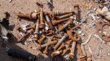 Paslı cıvatalar ve fındıklar yere saçılmış.