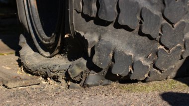 Hasarlı bir araba lastiği, patlak bir araba lastiği, bir traktör. Kapat.