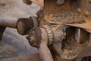 Çamur ve kirle kaplı bir aracın kirli ve yıpranmış direksiyon ya da süspansiyon bileşenlerine yakın çekim.