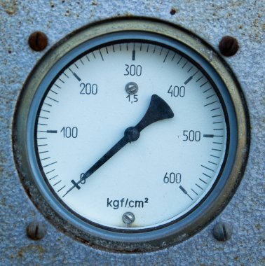 Dokulu metal bir yüzeye monte edilmiş yuvarlak analog basınç göstergesinin yakın çekimi.