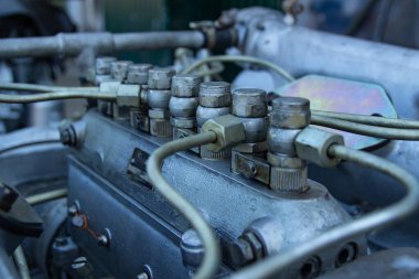 Dizel motora yakın çekim. Bir sıra silindirik yakıt pompaları, yakıt boruları ve çeşitli tesisatlar. Motor bloğu ve çevresindeki bileşenler aşınma ve kullanım belirtileri gösteriyor.