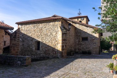 Güneşli bir günde Cantabria dağlarında geleneksel taş evleri olan Barcena Belediye Başkanı 'nın Güzel Köyü Kilisesi. Cantabria, İspanya.