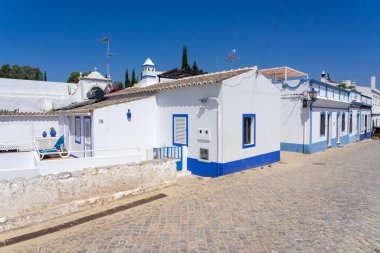 ALDEIA NOVA, PORTUGAL - Temmuz 06, 2022: Güneşli bir günde, Algarve bölgesinde beyaz ve mavi tipik evleri olan Aldeia Nova köyünün güzel caddesi,