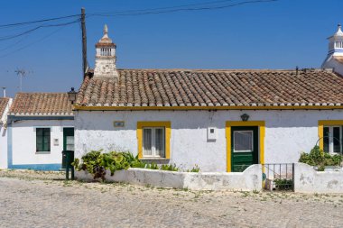 ALDEIA NOVA, PORTUGAL - Temmuz 06, 2022: Güneşli bir günde, Algarve bölgesinde beyaz ve mavi tipik evleri olan Aldeia Nova köyünün güzel caddesi,