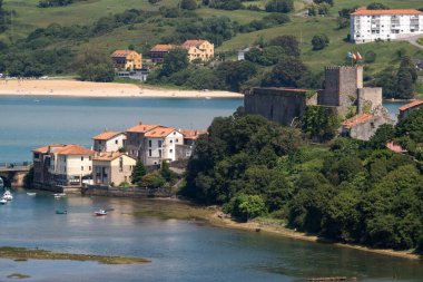 SAN VICENTE DE LA BARQUERA, İspanya - Haziran 06, 2021: San Vicente de la Barquera balıkçı köyü, bataklık, gemi ve teknelerle sakin bir günde şato, Cantabria, İspanya