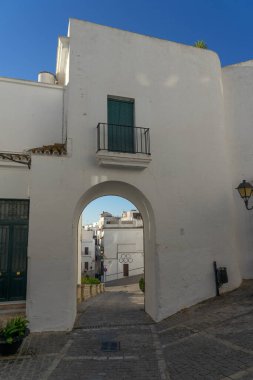 VEJER DE LA FRONTERA, İSPA - 09 Temmuz 2022: Güneşin doğuşunda, Cadiz ili, Endülüs, İspanya 'nın beyaz güzel köyü Vejer de la Frontera' nın tarihi merkezindeki köy kapısı
