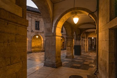 AVILES, SPAIN - 11 Şubat 2023: tarihi atari salonlarının alacakaranlıkta aydınlatıldığı, güzel Aviles kentinin eski Rivero caddesi, İspanya 'nın Asturias kentinde.