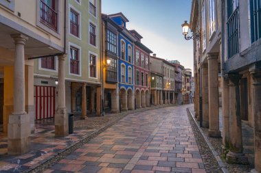 AVILES, SPAIN - 11 Şubat 2023: tarihi atari salonlarının alacakaranlıkta aydınlatıldığı, güzel Aviles kentinin eski Rivero caddesi, İspanya 'nın Asturias kentinde.