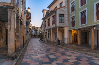 AVILES, SPAIN - 11 Şubat 2023: tarihi atari salonlarının alacakaranlıkta aydınlatıldığı, güzel Aviles kentinin eski Rivero caddesi, İspanya 'nın Asturias kentinde.