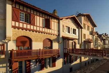 Jacques Thibaud 'daki geleneksel Bask evleri, gün batımında Frech Bask Bölgesi' ndeki Saint Jean de Luz güzel köyünde büyük plajın önünde yürürler..