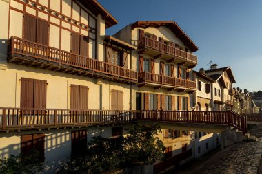 Jacques Thibaud 'daki geleneksel Bask evleri, gün batımında Frech Bask Bölgesi' ndeki Saint Jean de Luz güzel köyünde büyük plajın önünde yürürler..