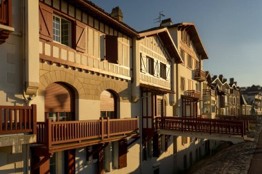 SAINT JEAN DE LUZ, FRANCE - SEPTEMBER 04, 2022: Jacques Thibaud 'daki geleneksel Bask evleri, Frech' in güzel Bask kasabası Saint Jean de Luz köyünde gün batımında büyük plajın önünde yürürler..